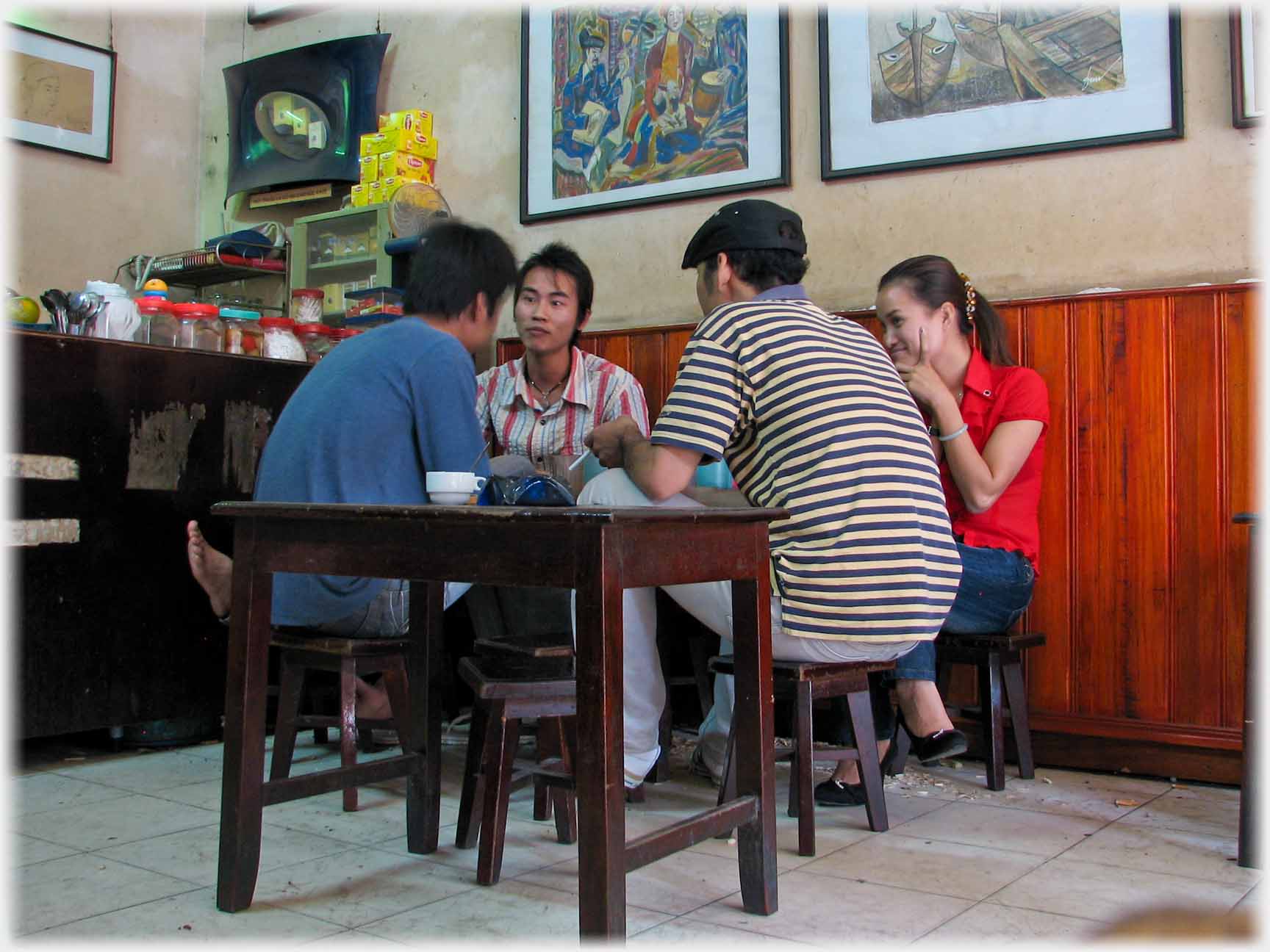 Three men and a woman leaning into a conversation, wall with pictures.