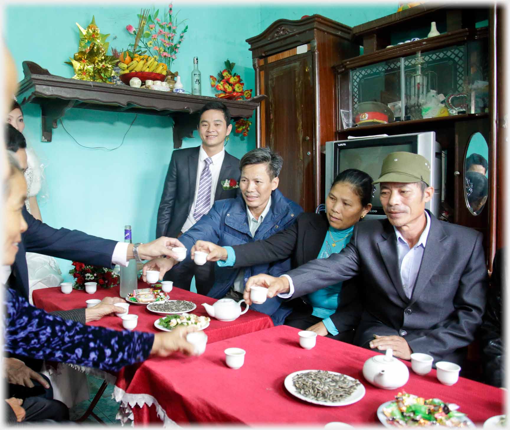 People sitting at table and reaching out and toasting with tea cups.