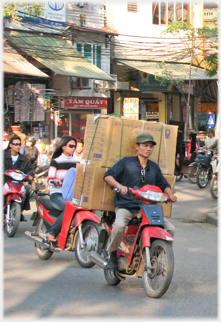 Two riders with sunglasses following man with two large boxes on the back.