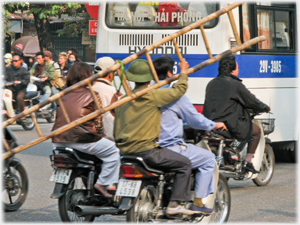 Pillion motorcyclist carrying ladder on his sholder.