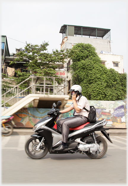 Man in dress trousers on expensive motorbike phoning.