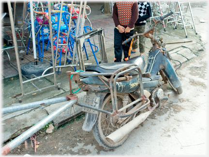 Very old motorbike parked at roadside.