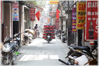 Motorbike in lane with 13 crates of Coca-cola on it.