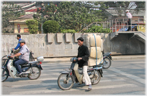 Man pushed to the very front of his seat by high pile of ?wooden blocks, with his legs stretched out to the sides.