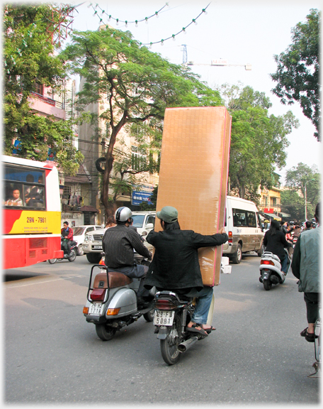 Rear view of man hugging bed on pillion seat.