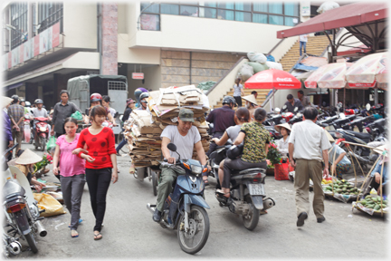 Man with pile of cardboard which is higher than his head.