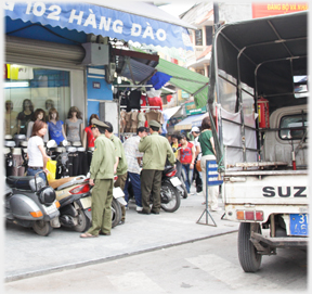 Uniformed man pointing sternly by woman and bike in shop entrance.