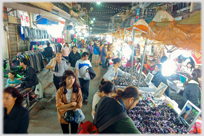 Electric bulbs lighting stalls with customers walking between.