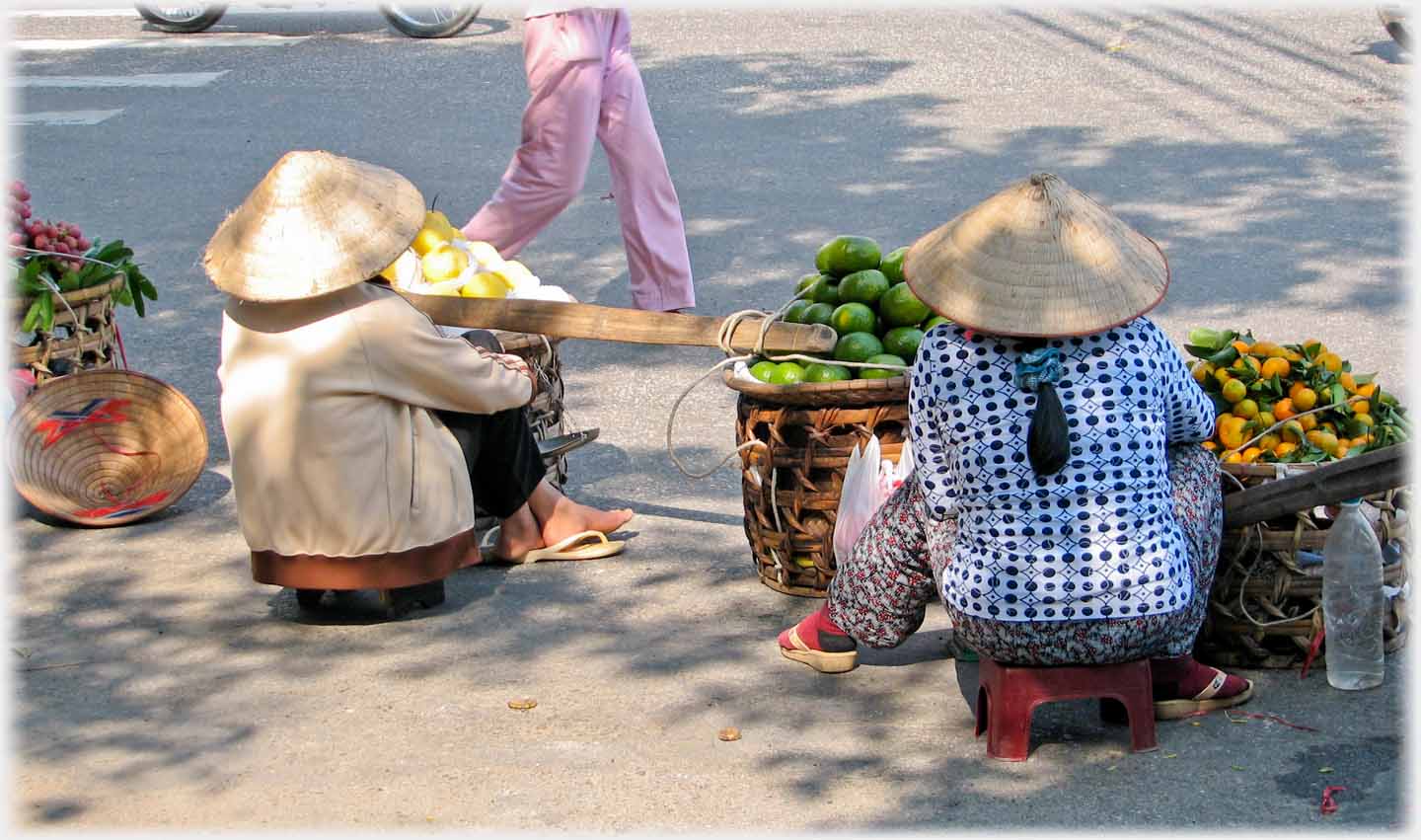 Rear view of two women sitting at roadside with the baskets of their panniers.