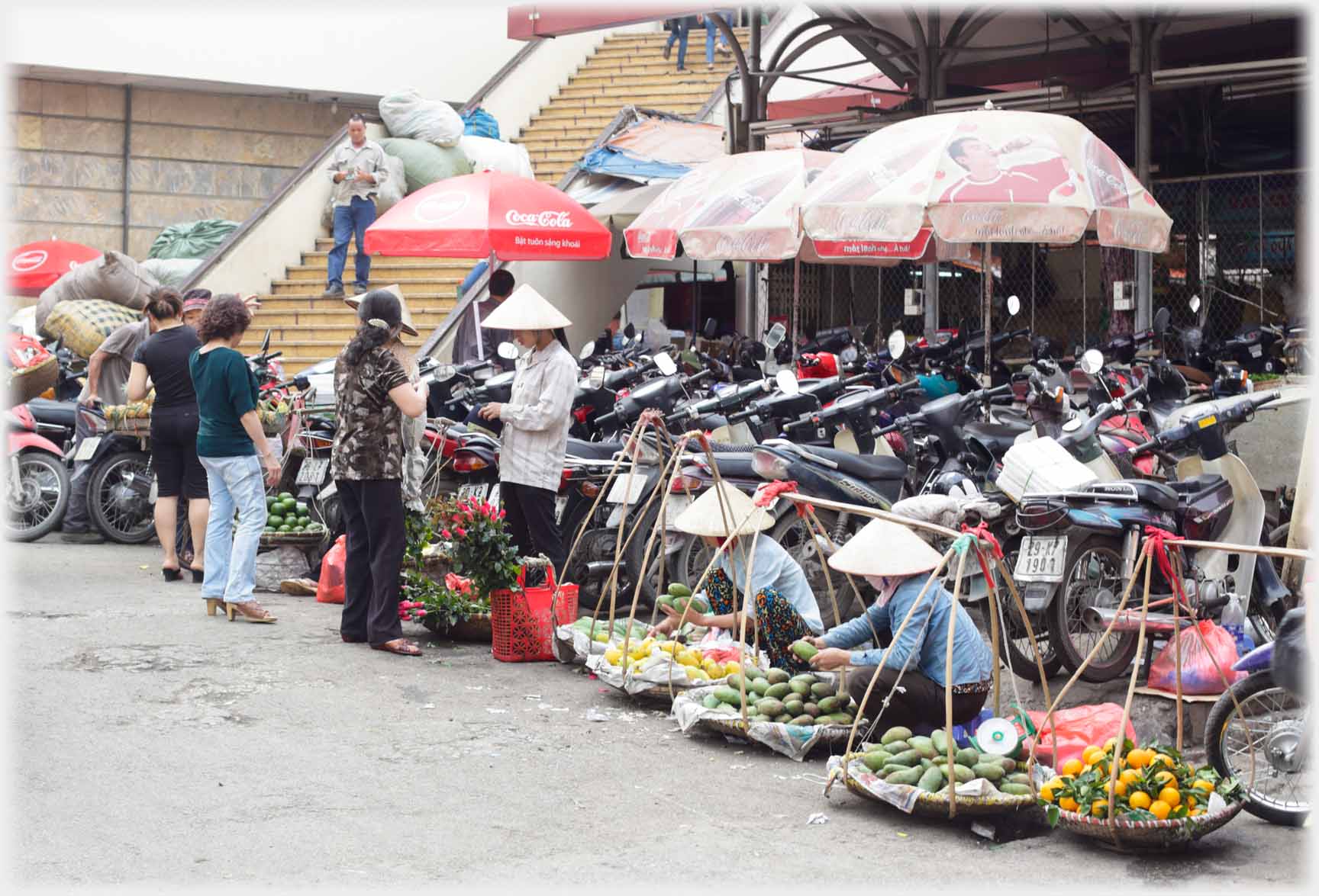 Fruit in panniers by motorcycle park.