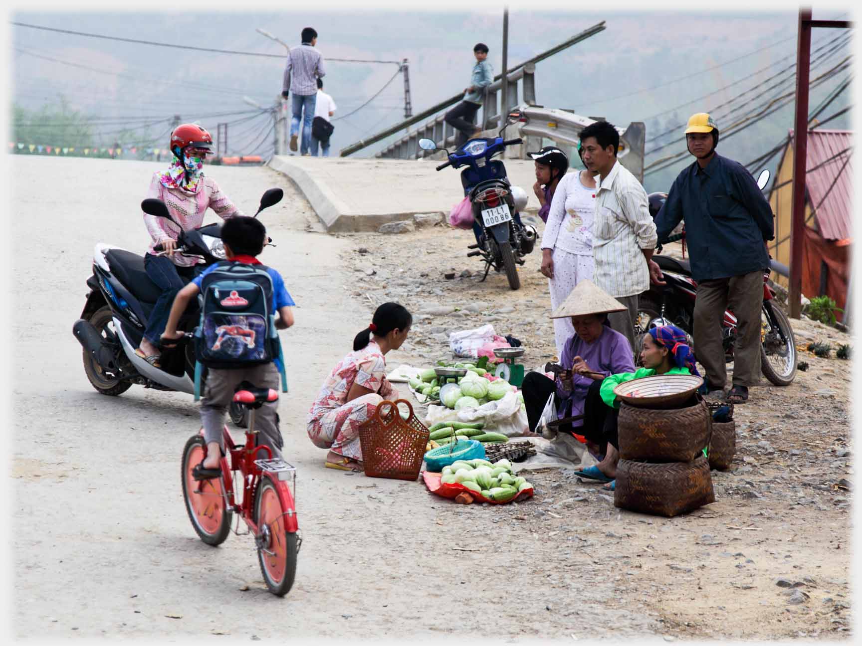 One seller with a number of customers and boy on bike.