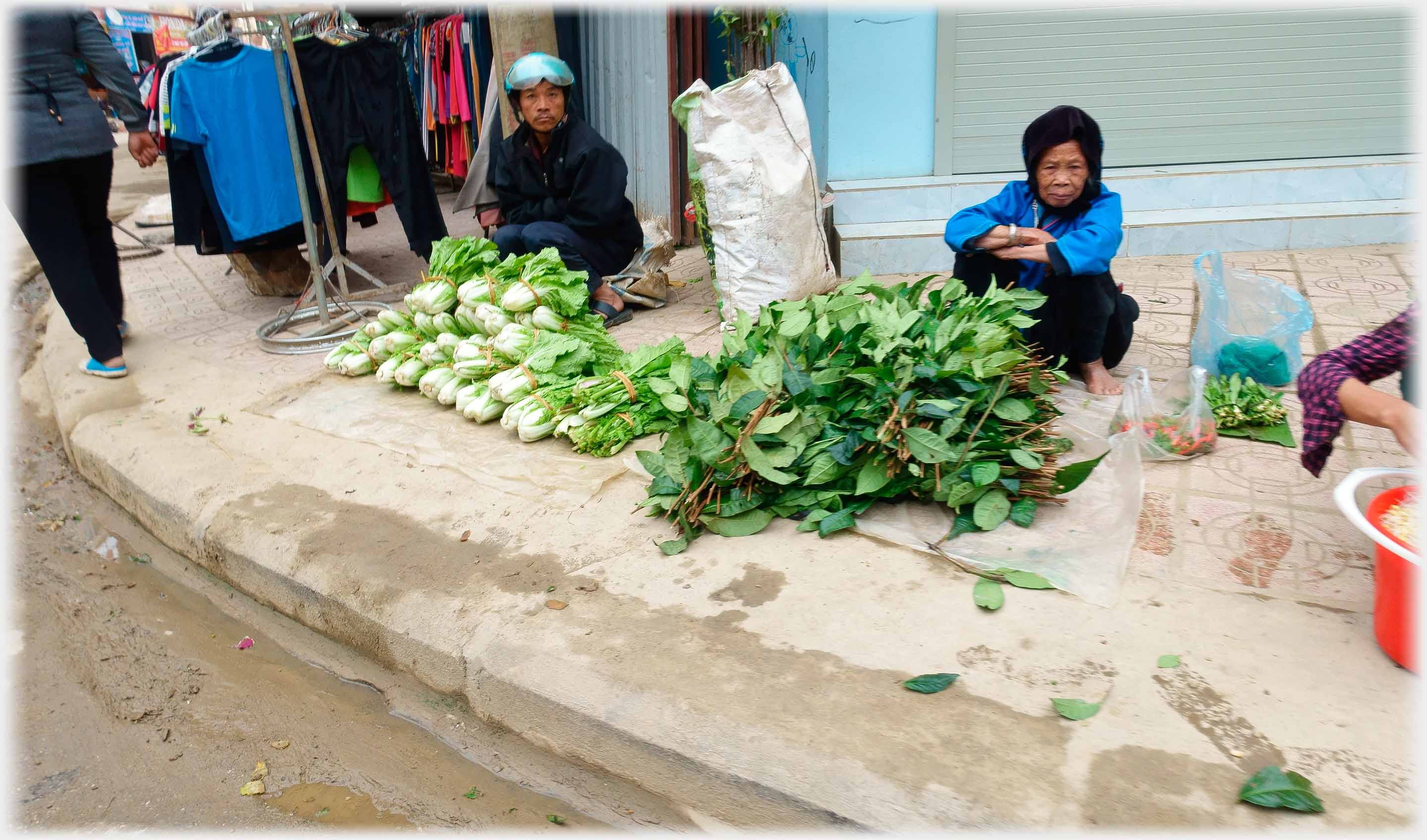 Man and woman behind piles of greens.