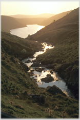 Sunset over distant loch with near-by river apparently running into it.