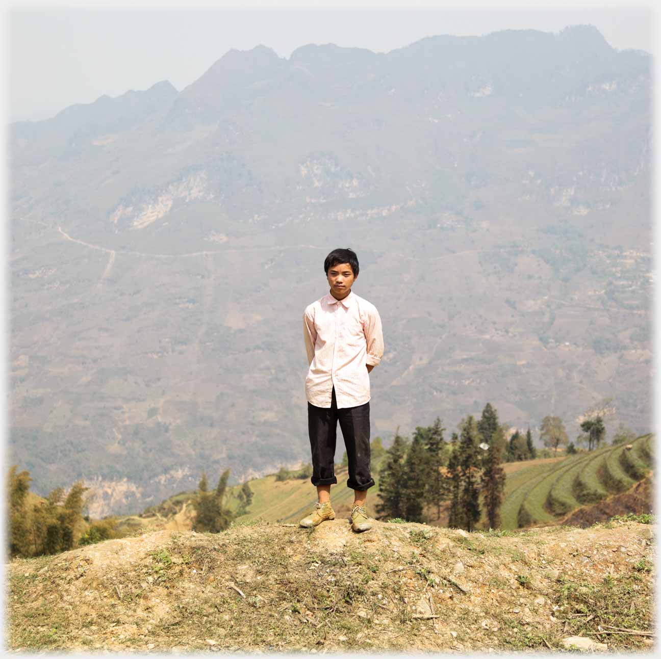Man standing on edge of slope with hands behind his back.