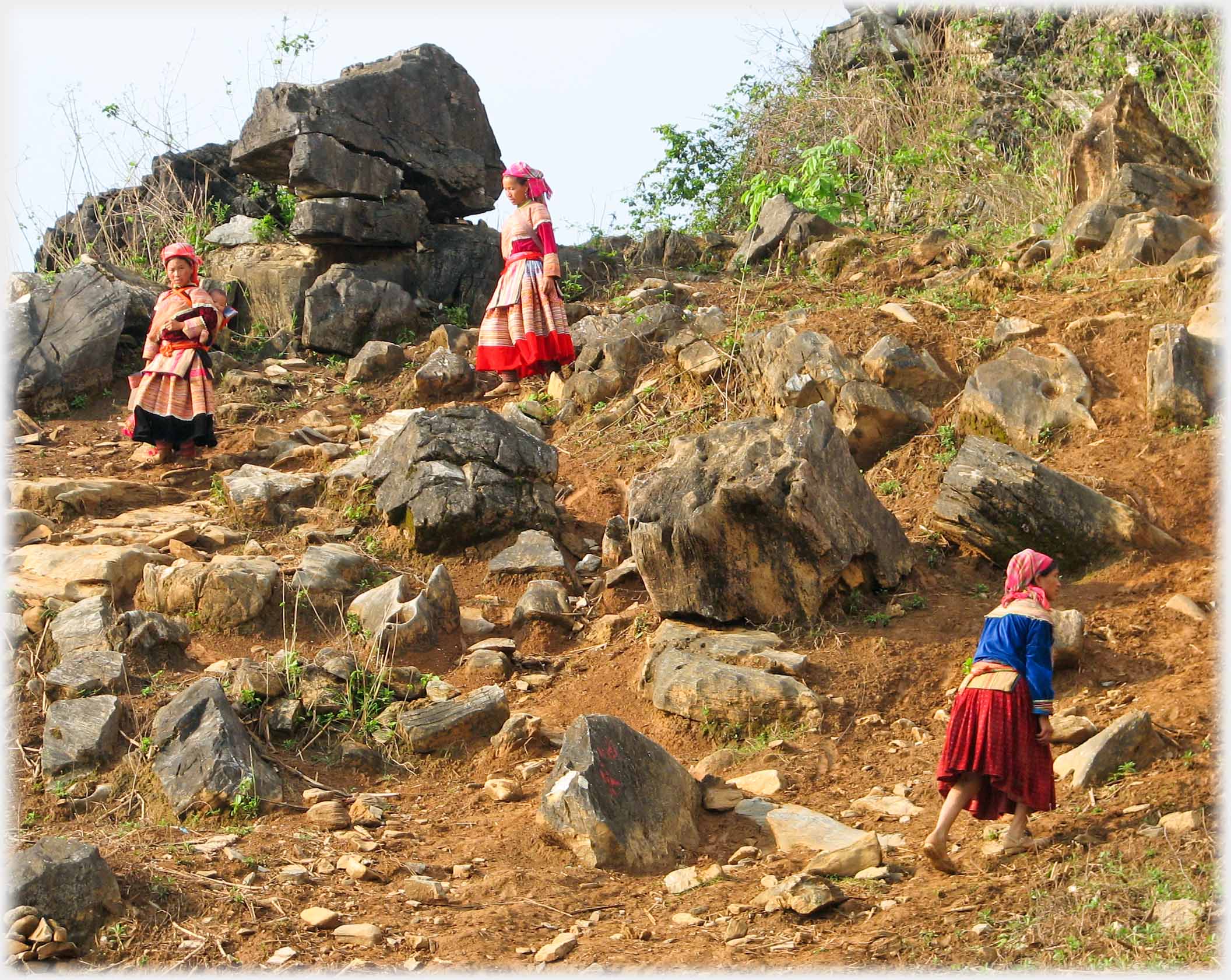 Two women coming down, one going up a hillside.