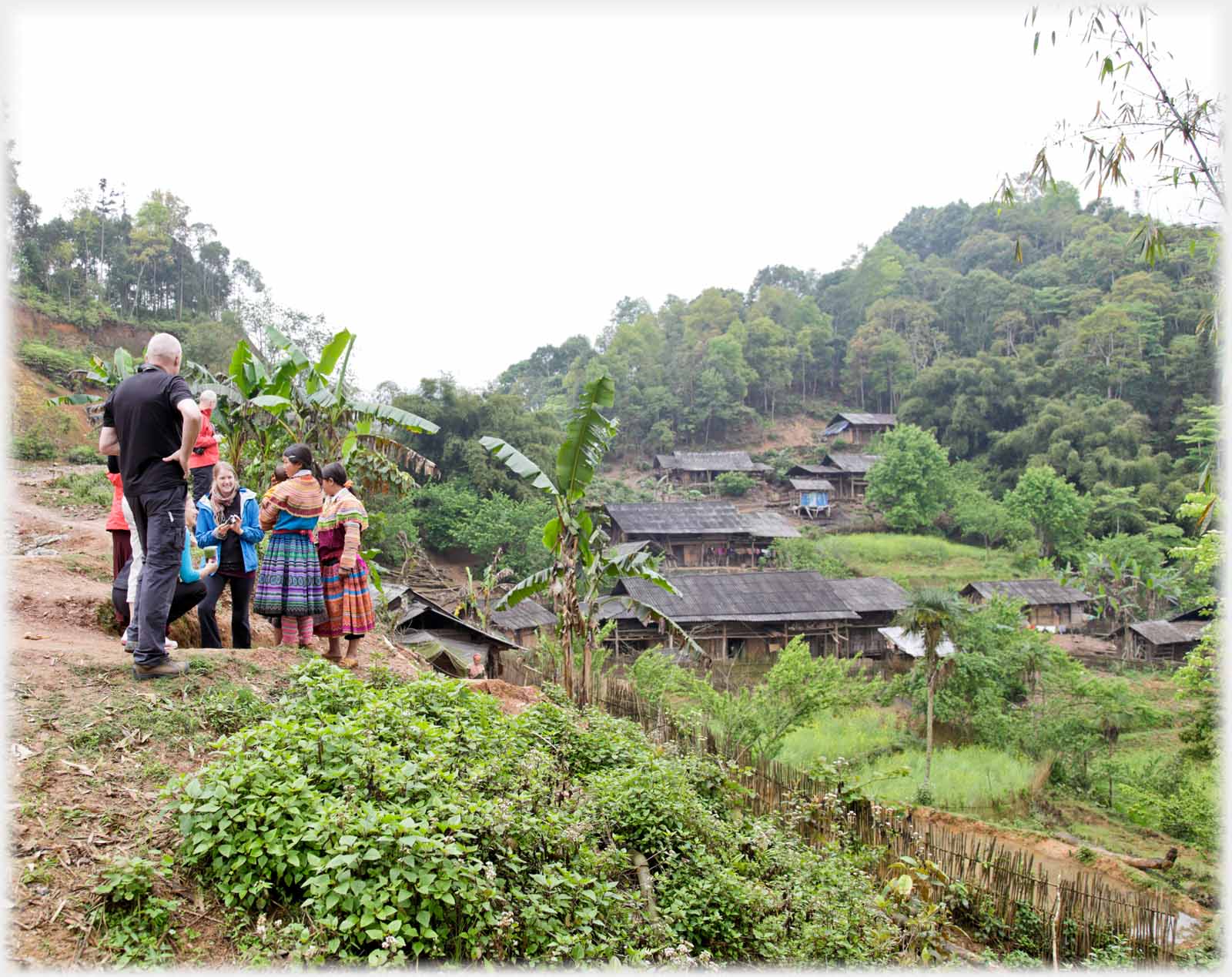 Group of women and man standng just above village.