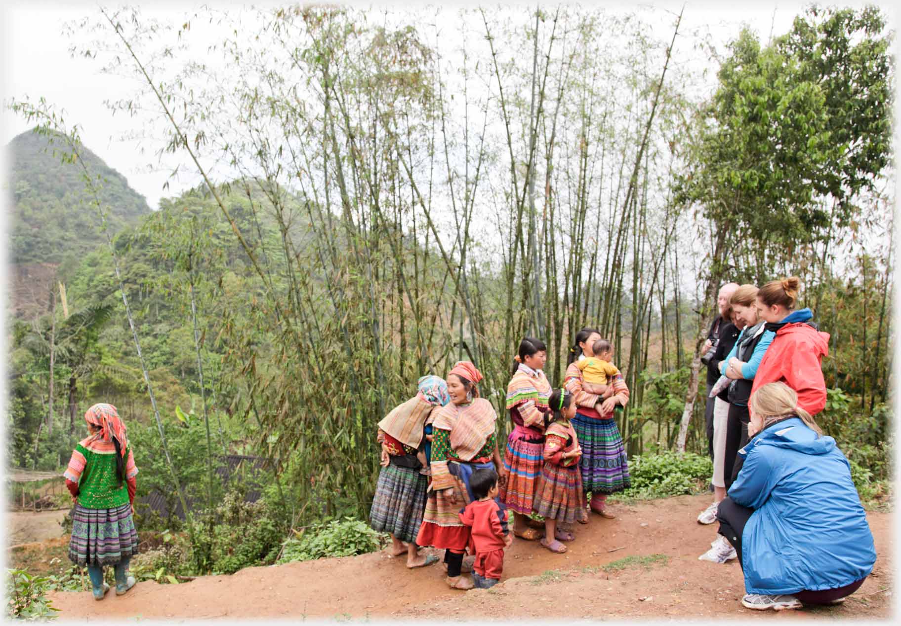 Group of women and children talking across to a line of westerners.