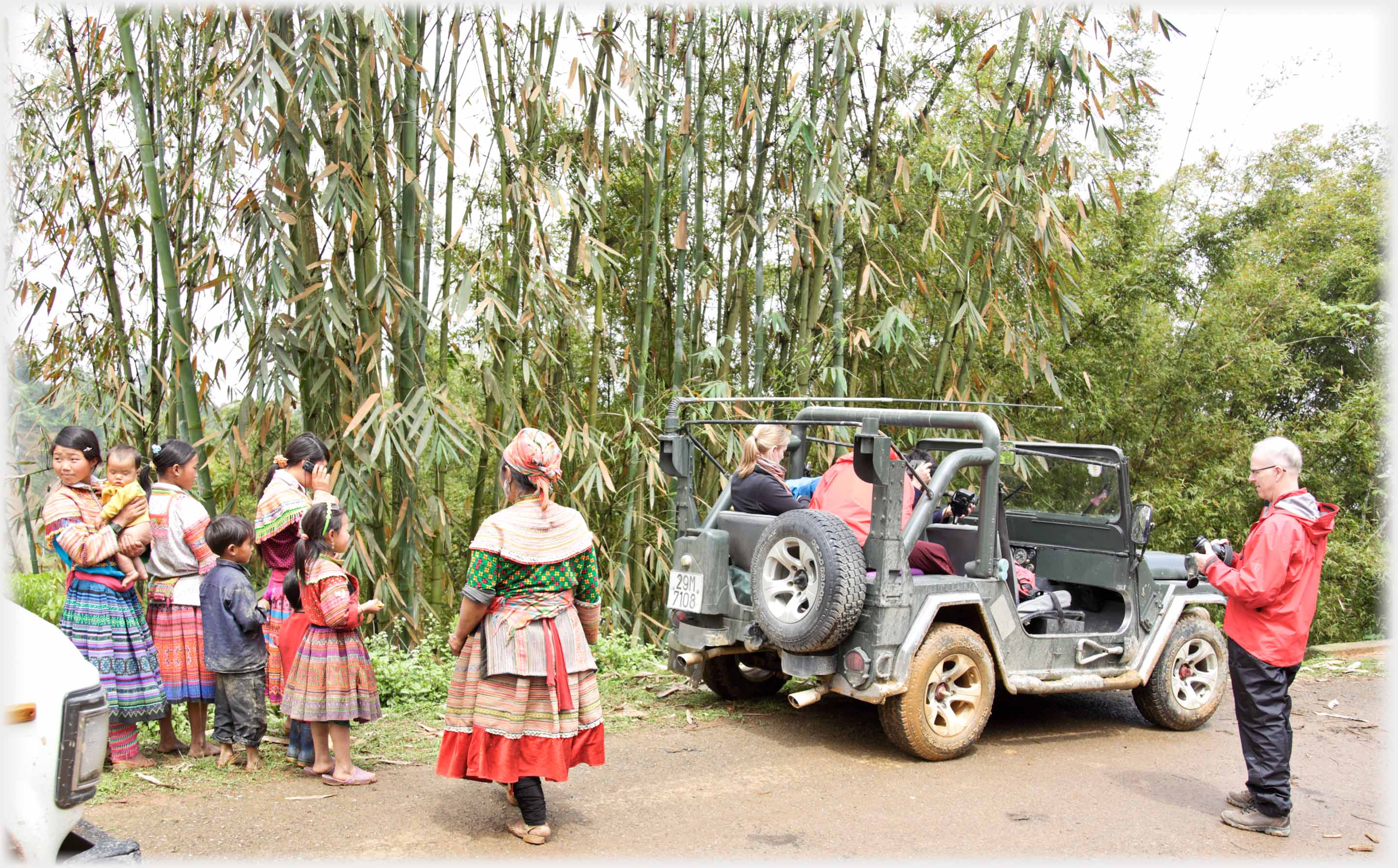 Group of Hmong women and children near  an open Jeep.