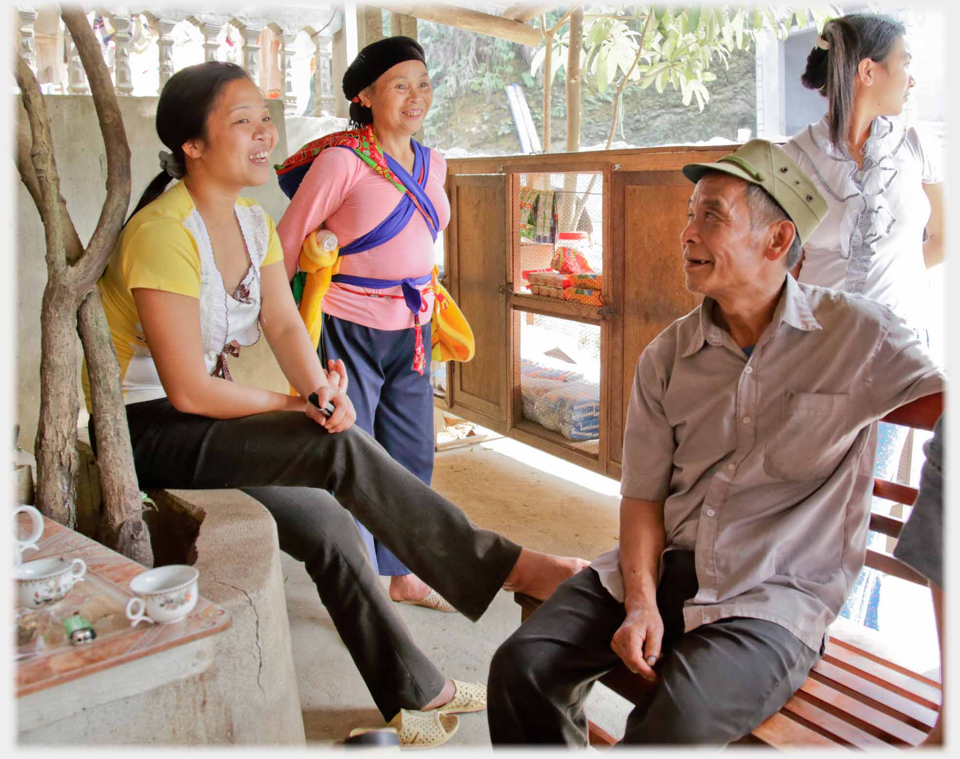 Older man talking to younger woman, two women standing.