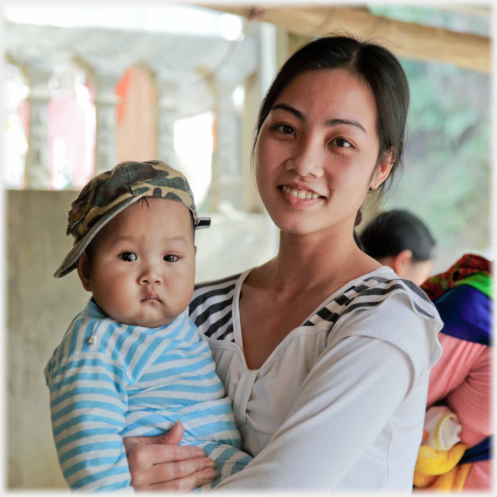 Woman holding infant which has rather a glum expression.
