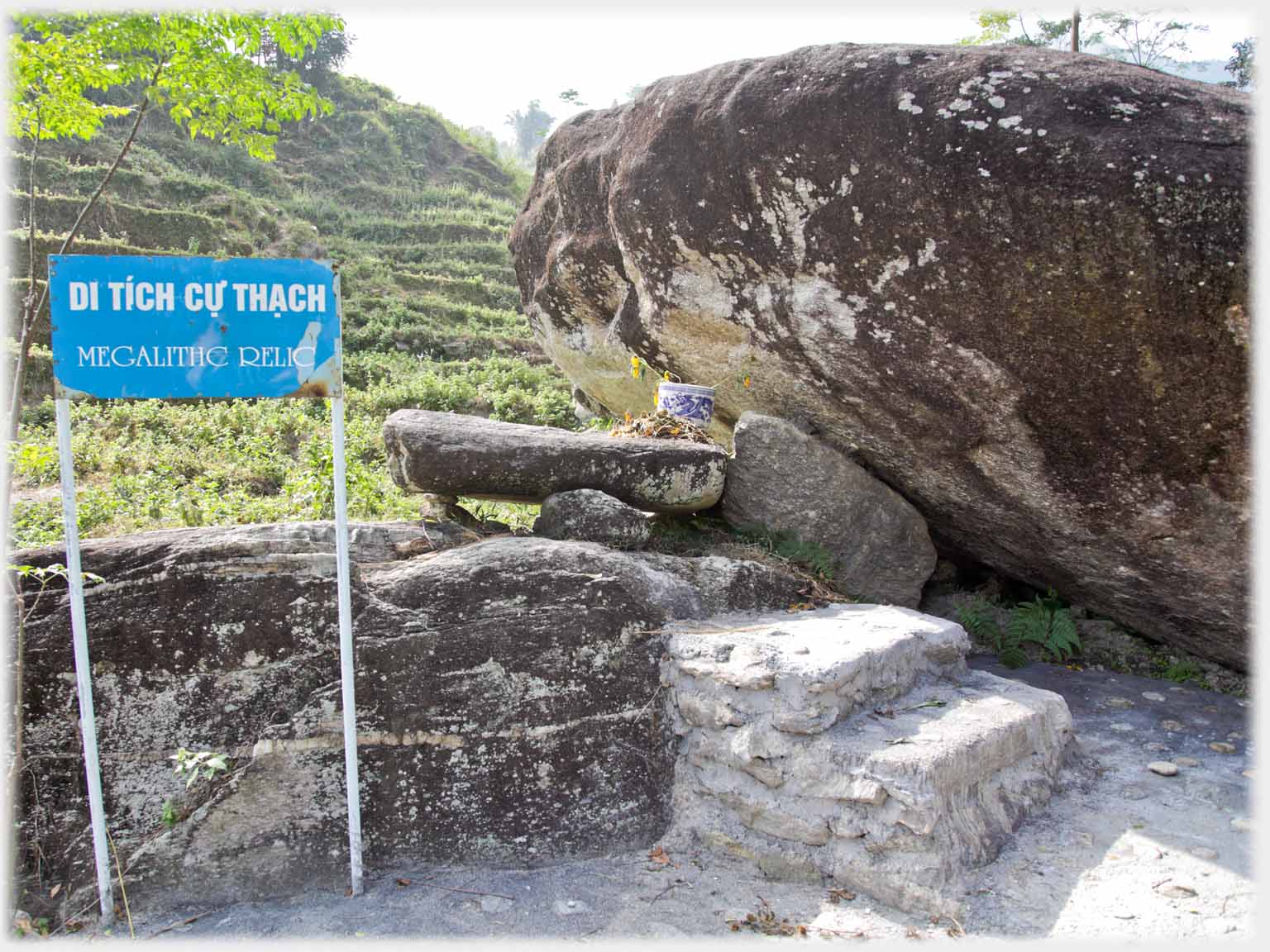 Sign at an angle and very large rock.