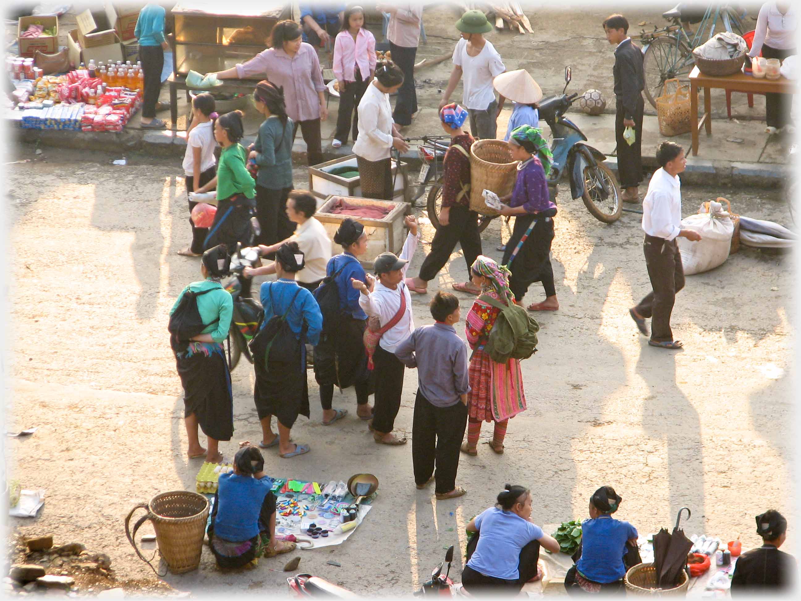 Varied group of people, talking, walking, selling.