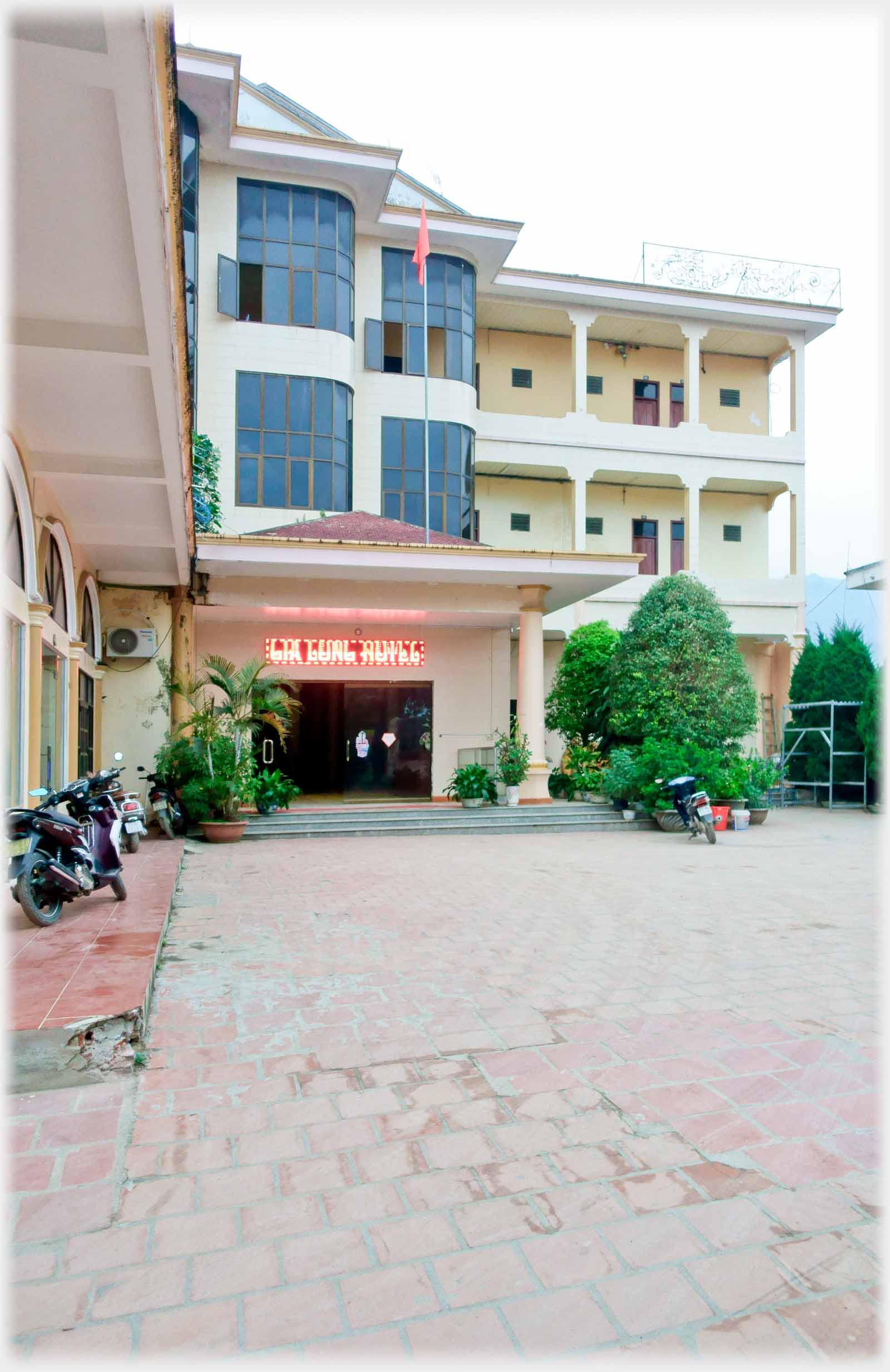Courtyard with three story hotel and entrance, sign over doorway.