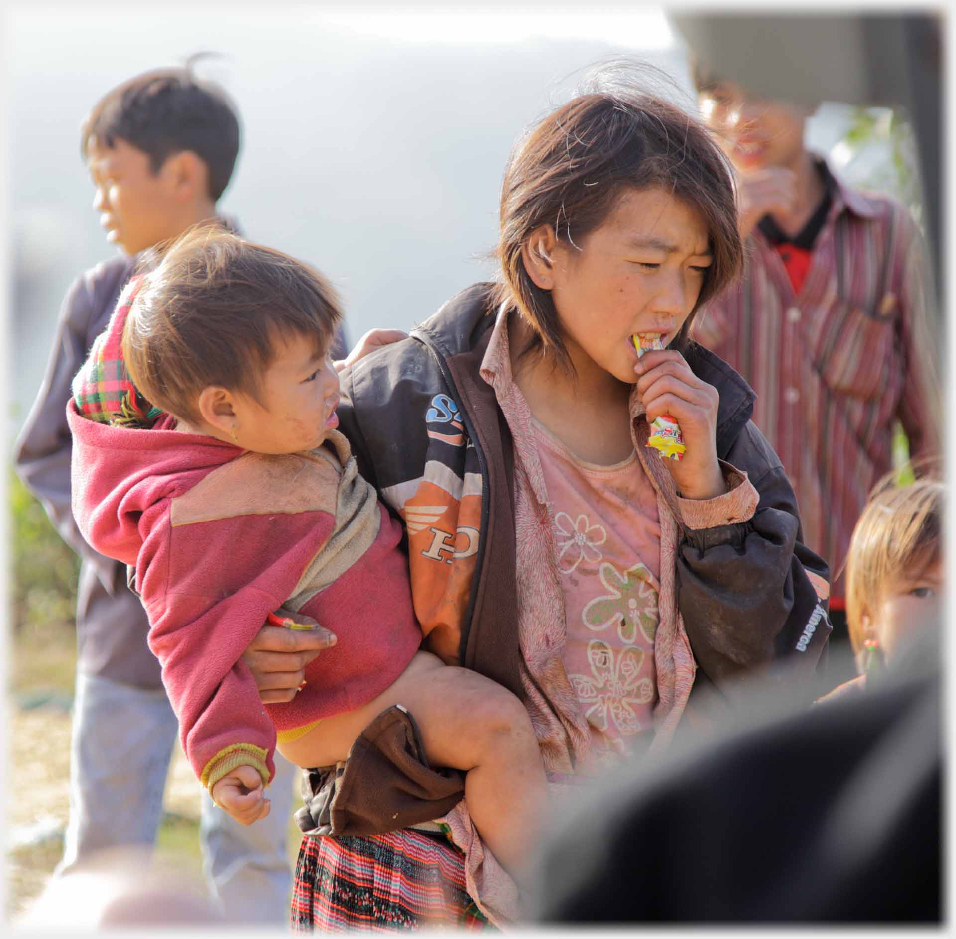 Woman chewing bar and holding infant.