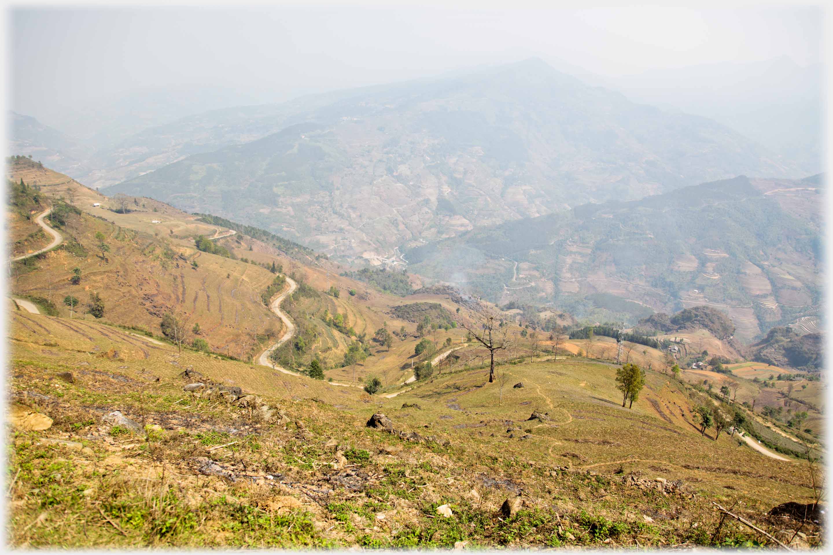 Hillside with sinuous road, far valleys with roads.