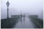 Two people on misty bridge.